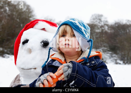 Un ragazzo con una carota per un naso snowmans Foto Stock