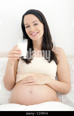 Donna incinta gustando un bicchiere di latte Foto Stock