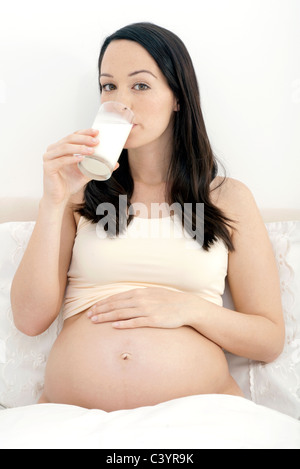 Donna incinta gustando un bicchiere di latte Foto Stock