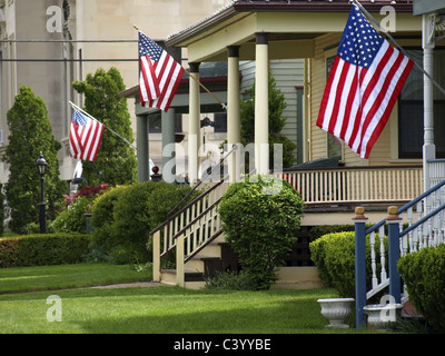 Bandierine americane sono battenti dal portico anteriore di case vittoriane su un americano vacanze molto patriottica. Foto Stock