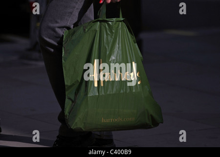 Una plastica Harrods shopping bag essendo portato da un acquirente Foto Stock