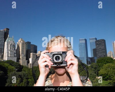 La donna a scattare foto in central park Foto Stock