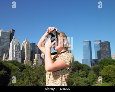La donna a scattare foto in central park Foto Stock