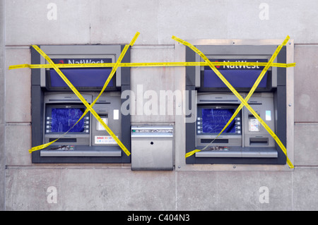 NatWest banca filiale locali esterno bancomat esterno due buco fuori ordine in parete coperto in nastro giallo Charing Cross London Inghilterra UK Foto Stock