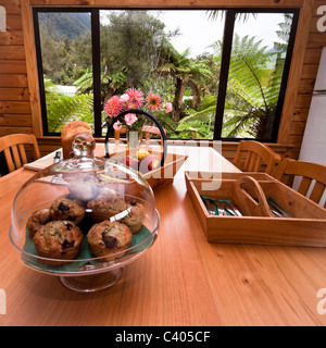 Tavolo da cucina con muffin, frutta, pane e posate. Foto Stock