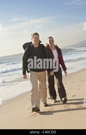 Giovani backpackers tenendo le mani alla spiaggia Foto Stock