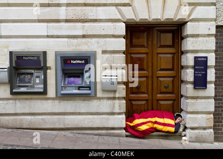 Senzatetto uomo dorme sulla soglia della National Westminster Bank, Norwich, Norfolk, Inghilterra, Regno Unito. Foto Stock