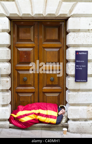 Senzatetto uomo dorme sulla soglia della National Westminster Bank, Norwich, Norfolk, Inghilterra, Regno Unito. Foto Stock