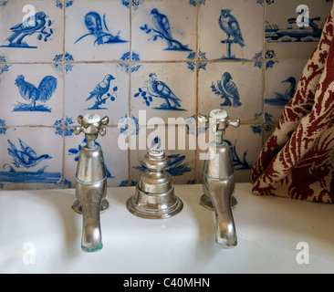 Il vecchio bagno i rubinetti di scarico e controllo con dipinto a mano blu Delft piastrelle ceramiche con motivi di uccelli Foto Stock