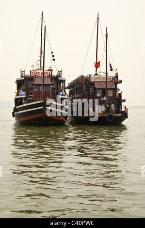 Vista verticale della tradizionale giunche in legno utilizzati per visite guidate ormeggiata in Halong Bay su una grigia giornata di nebbia. Foto Stock