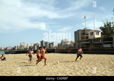 Cipro. Gli uomini giocano a calcio sulla spiaggia di fronte Varosha città fantasma in Famagosta, turca di Cipro del Nord Foto Stock