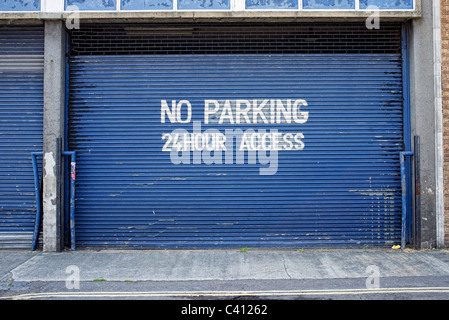 Blue porta di garage con parcheggio non accesso 24 ore segno dipinto sull'otturatore Foto Stock