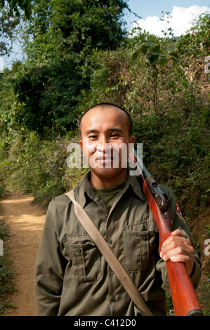 Hunter con la pistola sulla sua spalla sulla giungla via nel nord-est del Laos Foto Stock
