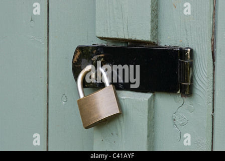 Vecchia cerniera a occhiello e lucchetto, in un vecchio capannone porta. Foto Stock