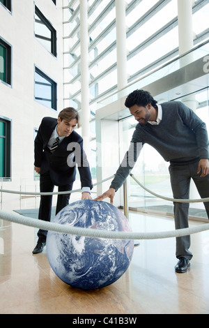 Imprenditori toccando sfera contenuta in spazio cintato Foto Stock