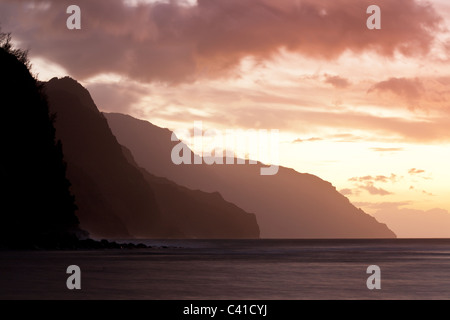 Nā Pali onde della costa dopo il tramonto. Il mare è calmato e le nuvole offuscata da una lunga esposizione della nettamente definita scogliere. Foto Stock