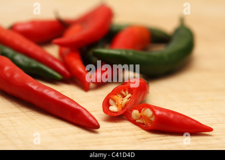 Rosso e peperoncini verdi su un tagliere di legno Foto Stock