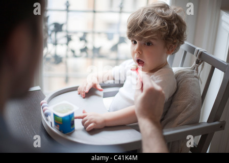 Il Toddler boy essendo alimentato yogurt Foto Stock