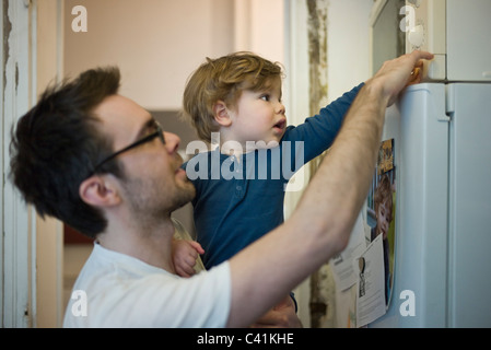 Il Toddler boy aiutando padre usando un forno a microonde Foto Stock