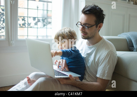 Padre e figlio giovane guardando al computer portatile insieme Foto Stock