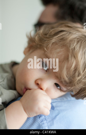 Il Toddler boy appoggiato la testa sul padre, spalla lacrime sul viso Foto Stock