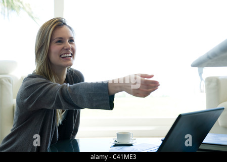 Donna raggiungendo per la carta che viene consegnato al suo da persona fuori-di-telaio Foto Stock