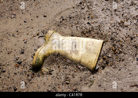 Un solitario wellington giallo (welly) boot scartati nella sabbia e fango con la bassa marea sulla spiaggia di Newlyn in Cornovaglia Foto Stock