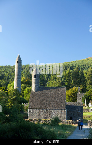 I visitatori al di sotto di San Kevin la chiesa e la torre rotonda, sito monastico di Glendalough, County Wicklow, Irlanda. Foto Stock