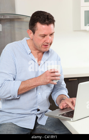 Uomo che lavora da casa tramite un computer portatile Foto Stock