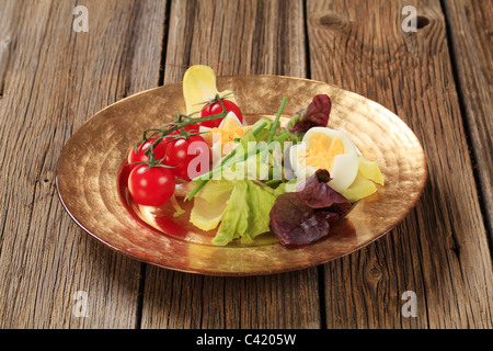 Ortaggi freschi e uova sode sulla piastra di oro Foto Stock