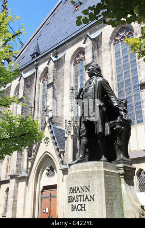 Statua del compositore classico Johann Sebastian Bach nella sua città natale di Leipzig, Germania. Dietro di lui è la celebre chiesa di San Tommaso. Foto Stock