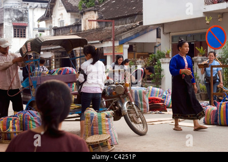 Le persone sono arrivate a vendere merci su un marciapiede in una trafficata strada del mercato in Laos comunista. Foto Stock