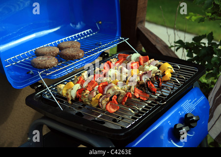 Barbecue con verdure su spiedini e hamburger Foto Stock