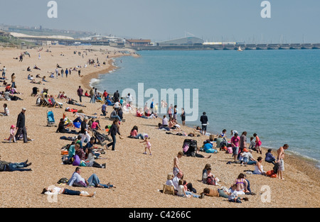 La gente seduta sulla spiaggia di Brighton Foto Stock