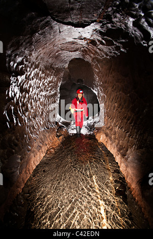 Donna speleologo nel passaggio di flusso nella grotta del Galles REGNO UNITO Foto Stock