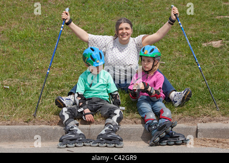 Una donna di mezza età e i suoi due figli piccoli avente una pausa dal Nordic Walking e pattinaggio in linea Foto Stock