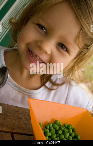 Ragazza giovane felicemente mangiare piselli Foto Stock