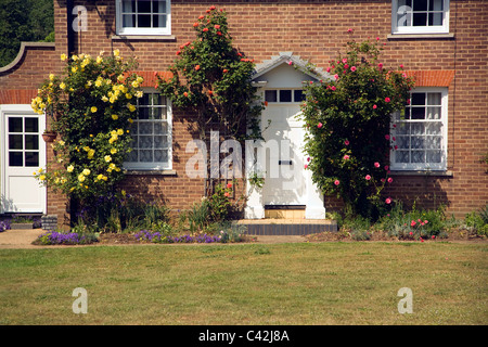 Le rose crescono attorno alla porta di un cottage di campagna, Shottisham, Suffolk, Inghilterra Foto Stock