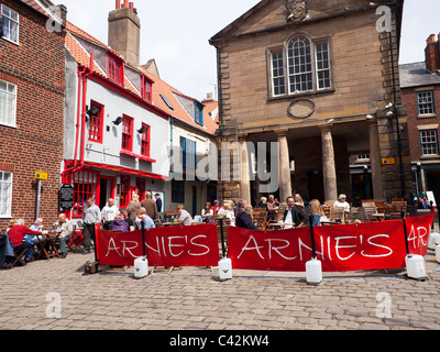 Turisti che si godono una sosta e ristoro presso i tavoli fuori Arnie's Bistro Café in luogo di mercato Whitby North Yorkshire Foto Stock