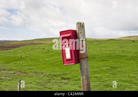 Voe, Northmavine, isole Shetland, Scotland, Regno Unito. Rosso rurale Royal Mail postbox su un wonky post. Foto Stock