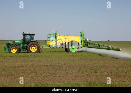 La spruzzatura di un erbicida in un campo di grano Foto Stock