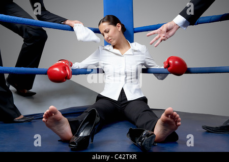 Ritratto di stanchi imprenditrice in guantoni da pugilato dormire su di pugilato ring dopo il gioco duro Foto Stock