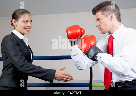 Ritratto di imprenditore aggressivo nella boxe Guantoni boxe combattimenti con positivi femmina con il suo braccio teso per stretta di mano Foto Stock