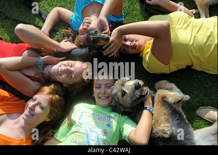 Il gruppo di donne sorridente con due cani, sdraiati su un prato. Germania. Foto Stock