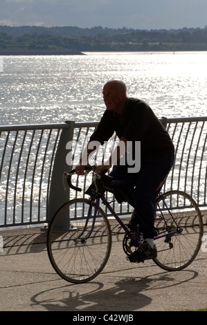 Silhouette di una persona in sella a una moto da sul fiume Mersey. Foto Stock