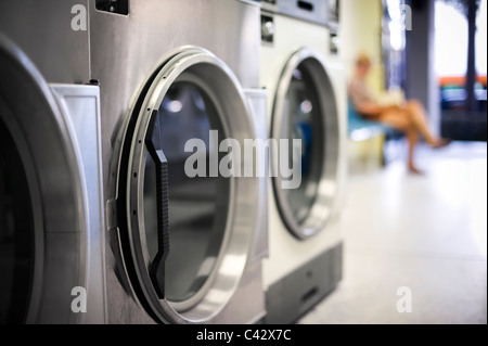 Ragazza in attesa in lavanderia a gettoni Foto Stock