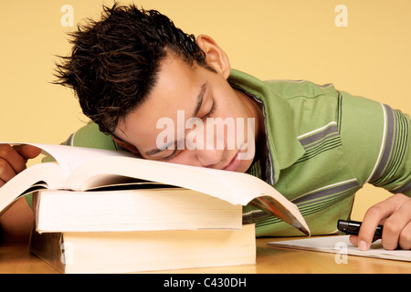 Close-up di un ispanico 19 anni studente dormendo sui libri invece di studiare. Foto Stock