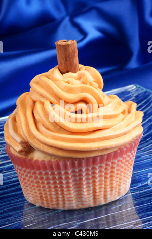 La carota e la cannella cupcake su un piatto di vetro su uno sfondo blu Foto Stock