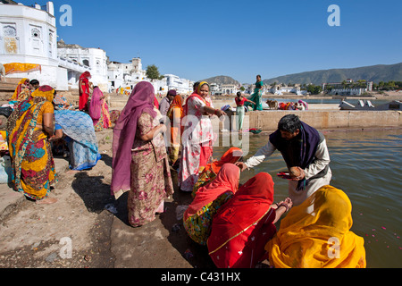 Le donne indiane facendo una offerta rituale (puja). Lago di Pushkar. Il Rajasthan. India Foto Stock