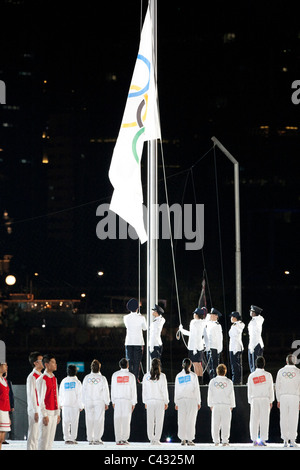 La bandiera olimpica è sollevata durante il 2010 Singapore Olimpiadi della Gioventù cerimonia di apertura. Foto Stock